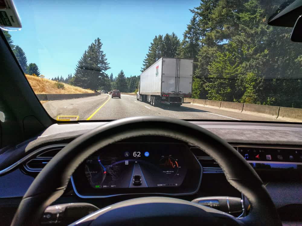 A Tesla on the highway with the Autopilot road visualization on the dash